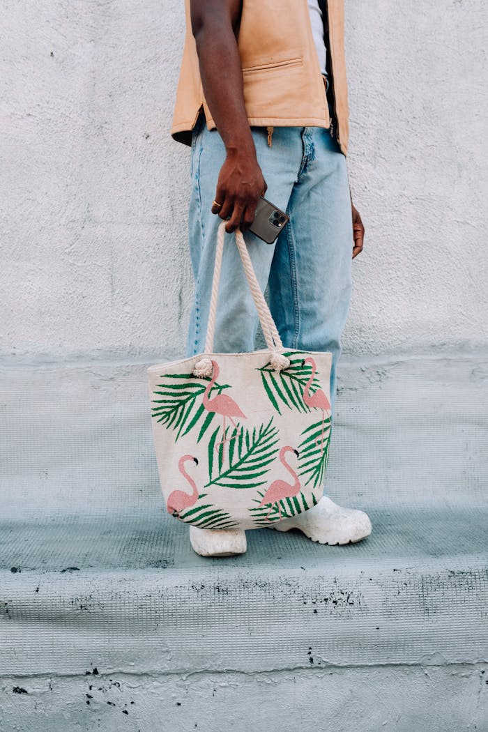 Man in casual attire holding a flamingo print shopping bag, showcasing trendy design.