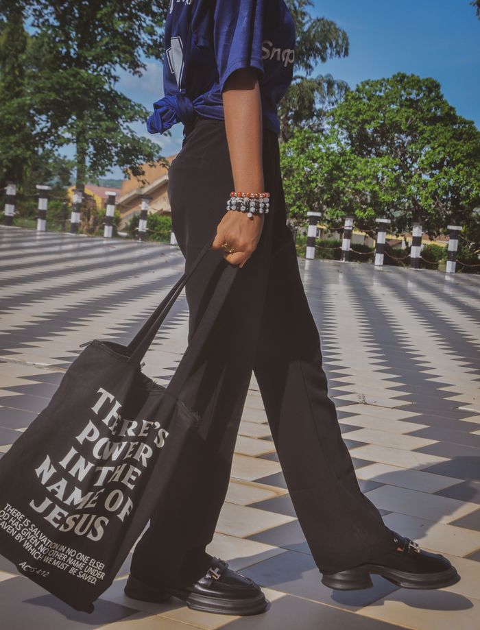 A person strolls outdoors with a bold, inspirational message on their tote bag.
